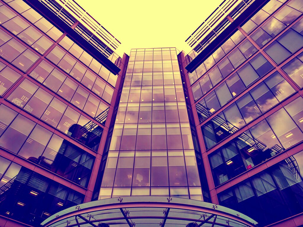 Home Dramatic angle shot of a modern glass office building with reflective windows.